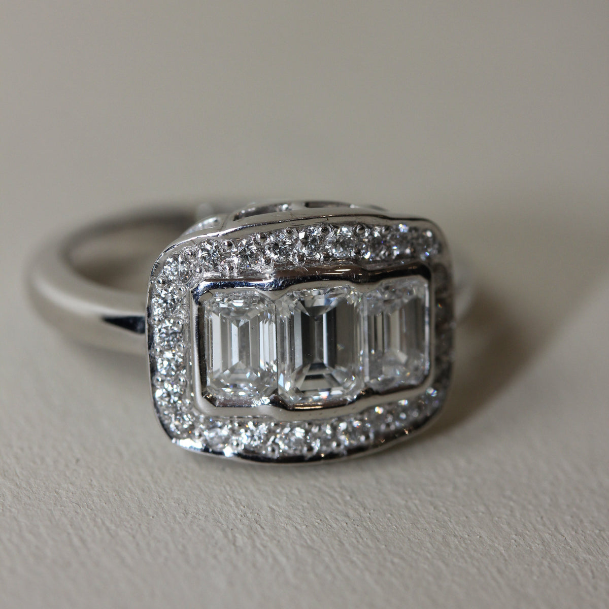 18CT WHITE GOLD EMERALD CUT DIAMOND HALO TRILOGY RING